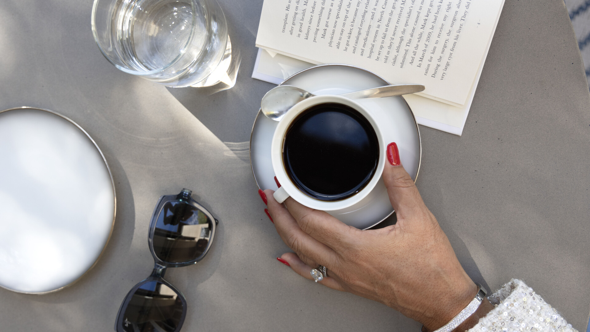 Coffee, book, sunglasses, and red manicure